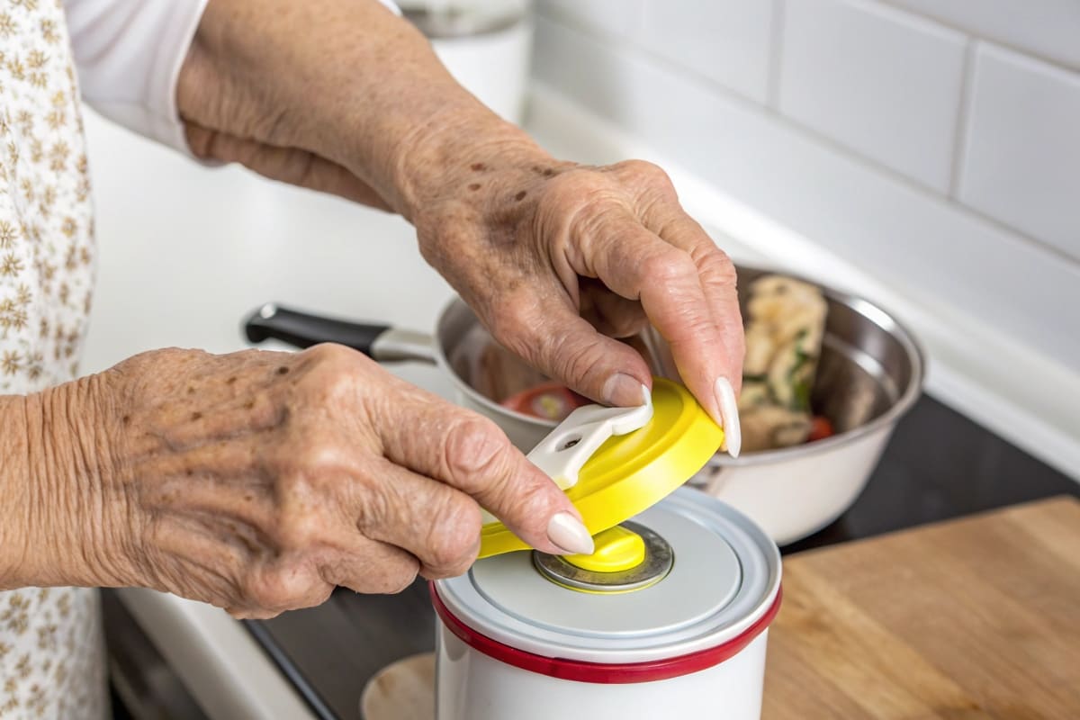 An elderly person's hands easily peeling back an induction seal with a prominent, easy-to-grip tab