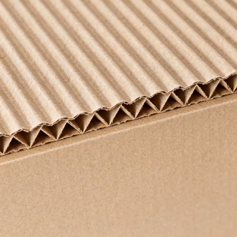 Internal Structure of a Corrugated Box A close-up shot showing the internal zig-zag "flute" layer of a corrugated cardboard sheet, sandwiched between two flat liners